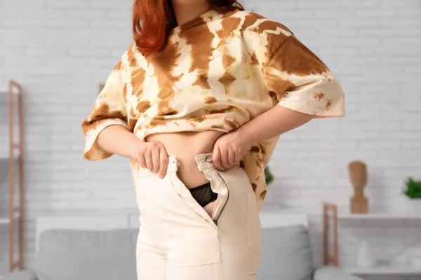 Image of woman trying to do her trousers up after pregnancy weight gain Dudley